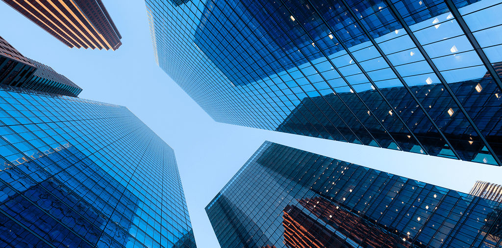 Upwards shot of a blue sky, framed by glass skyscrapers